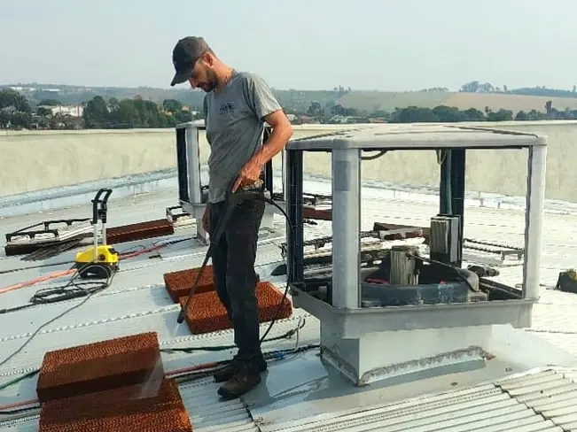 Técnico da EcoPlus fazendo a manutenção de um climatizador aberto no telhado