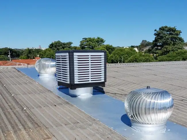 Climatizador e exaustores no telhado de uma empresa, com céu azul